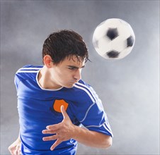 Hispanic soccer player hitting ball with head