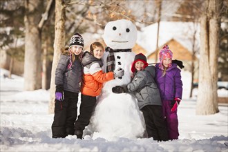 Caucasian family building snowman in snow