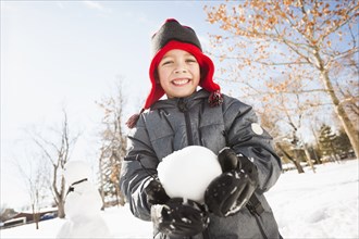 Caucasian boy holding snowball outdoors