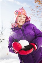 Caucasian girl holding snowball outdoors