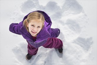Caucasian girl making snow angel outdoors