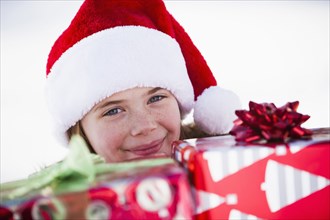 Caucasian boy in Santa hat holding Christmas presents
