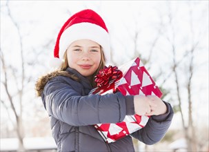 Caucasian girl in Santa hat holding Christmas present