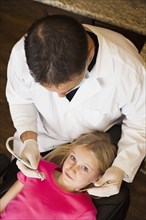 Caucasian dentist examining girl's teeth in office