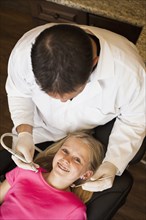 Caucasian dentist examining girl's teeth in office