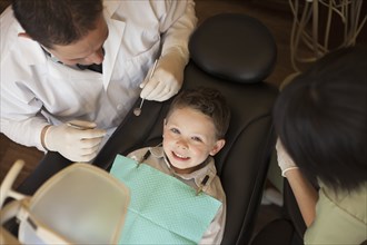 Dentist and nurse examining boy's teeth in office