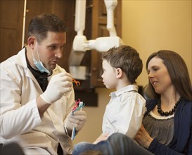 Dentist and nurse examining boy's teeth in office