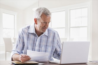 Caucasian man paying bills with laptop
