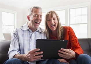 Caucasian couple using tablet computer on sofa