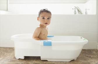 Mixed race boy having bath in tub