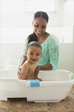 Mother bathing baby son in tub