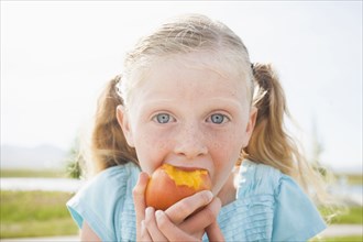 Caucasian girl eating fruit outdoors