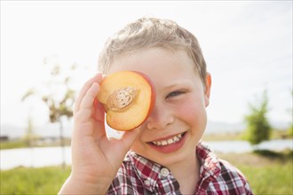 Caucasian boy holding fruit over eyes