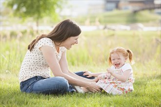 Caucasian mother and daughter playing in grass
