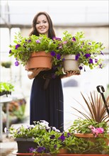 Caucasian woman holding potted flowers in plant nursery