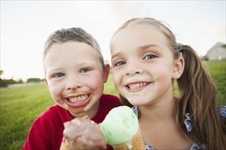 Caucasian children eating ice cream outdoors