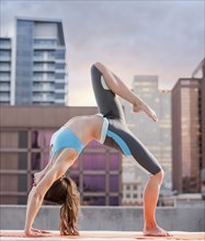 Caucasian woman practicing yoga on urban rooftop