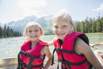 Caucasian girls wearing life jackets in canoe