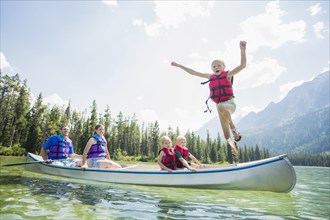 Caucasian boy jumping from canoe into lake