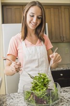 Caucasian woman tossing salad in kitchen