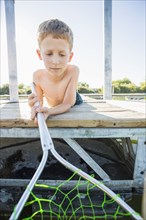 Caucasian boy using fishing net on dock