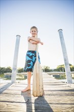 Caucasian boy holding paddle on dock