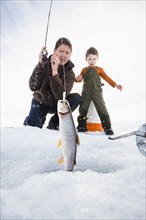 Caucasian father and son ice fishing