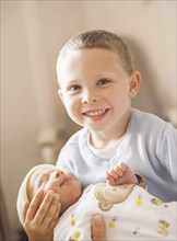 Caucasian boy holding newborn baby brother
