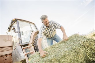 Caucasian farmer hauling hay bale