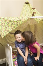 Caucasian children kissing in blanket fort