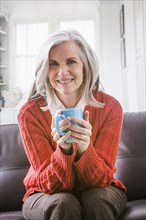 Portrait of Caucasian woman drinking coffee on sofa