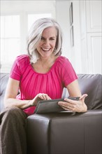 Caucasian woman using digital tablet on sofa