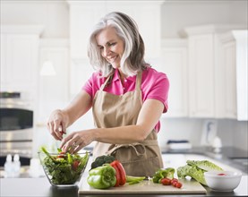Caucasian woman preparing salad in kitchen