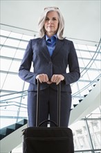 Portrait of confident Caucasian businesswoman with suitcase