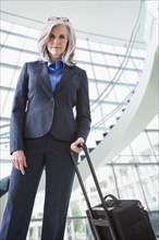 Portrait of confident Caucasian businesswoman with suitcase