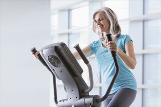 Happy Caucasian woman on elliptical trainer at gym