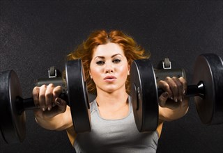 Caucasian woman doing chest presses with dumbbells in gym