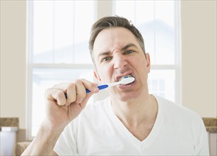 Caucasian brushing his teeth in bathroom
