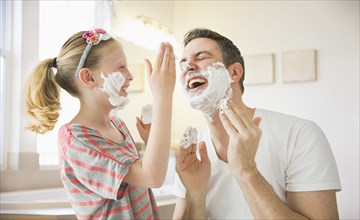 Caucasian father and daughter playing with shaving cream