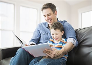 Caucasian father and son reading on sofa