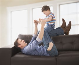 Caucasian father and son playing on sofa