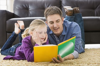 Caucasian father and daughter reading in living room