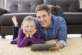 Caucasian father and daughter using tablet computer in living room