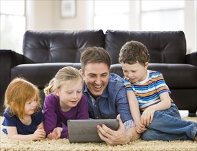 Caucasian father and children using tablet computer in living room