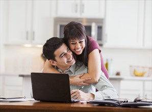 Hispanic couple hugging at laptop