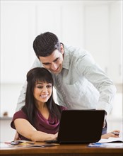 Hispanic couple using laptop at desk