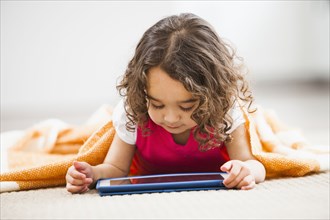 Mixed race girl using tablet computer on living room floor