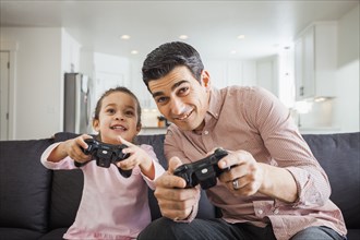 Father and daughter playing video games in living room