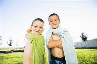 Caucasian boys wearing towel capes in backyard