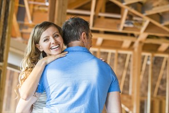 Caucasian couple hugging in house under construction